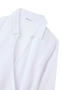 Blusa bianca con colletto aperto, maniche corte e una texture di tessuto liscia. Etichetta visibile che indica il marchio "Terranova" e la taglia "S".