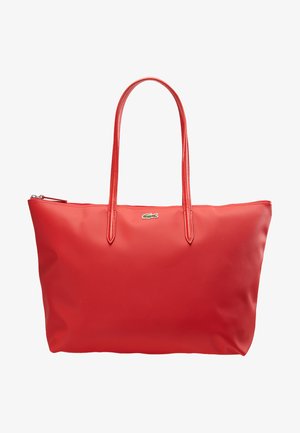 Raudona sintetinio audinio rankinė su ilgomis rankenomis, užtrauktuku ir tekstūruota paviršiumi. Priekyje yra mažas metalinis logotipo akcentas.