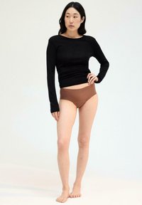 Zwarte top met lange mouwen en bruine high-waisted slips. De top is aansluitend met een gladde textuur, terwijl de slips een naadloos ontwerp hebben.