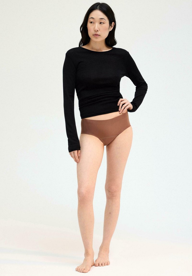 Zwarte top met lange mouwen en bruine high-waisted slips. De top is aansluitend met een gladde textuur, terwijl de slips een naadloos ontwerp hebben.