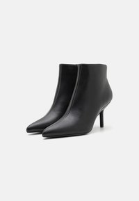 Botines de cuero negro con punta afilada, diseño ajustado y tacón delgado. Textura suave con detalles de costura mínimos.