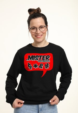 Černá mikina s velkým červeným grafickým bublinou s textem a symboly v tučné bílé a černé barvě. Měkká, pohodlná tkanina.