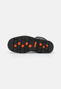 Semelle de chaussure noire avec un motif de semelle texturé, présentant des accents orange. Matériau en caoutchouc durable conçu pour la traction et la stabilité.