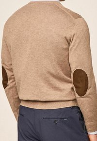 Beige sweater with a textured finish, featuring brown suede elbow patches and a crew neckline. Notable ribbed hem and cuffs.