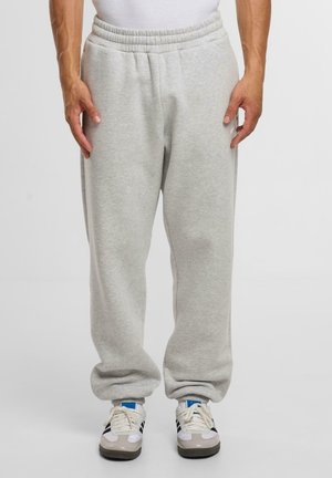 Grijze sweatpants van zachte stof met een elastische tailleband, zijzakken en een ontspannen pasvorm, gecombineerd met wit-grijze sportschoenen.