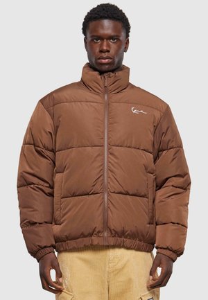 Brown puffer jacket with a high collar, zip front, quilted texture, and logo accent on the chest. Ribbed hems and cuffs.