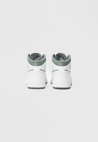 Białe wysokie trampki z jasnymi zielonymi akcentami i teksturowanym językiem; gładki materiał skóry; gumowa podeszwa z wzorzystym bieżnikiem.