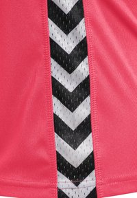 Top deportivo rosa con un patrón de chevron texturizado en blanco y negro a lo largo del costado, fabricado con un material suave y ligero.
