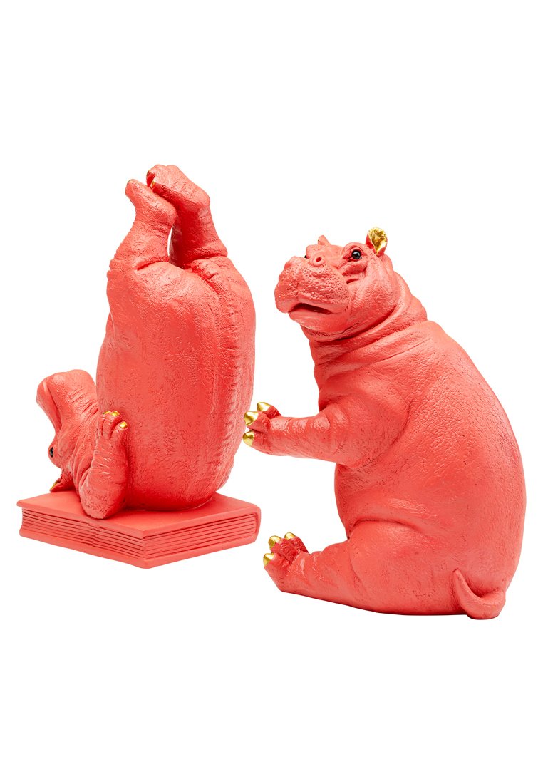 Zwei korallenfarbene Nilpferdfiguren, eine aufrecht mit einem Buch als Basis, mit strukturierten Oberflächen und goldenen Akzenten an Ohren und Klauen.