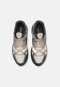 Ténis Reebok Premier Road Plus VI com parte superior em bege, branco e azul-marinho, com textura em malha, bico redondo e sola acolchoada.