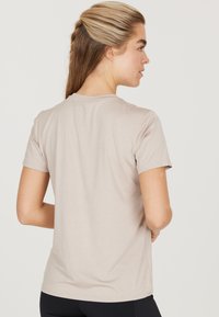 Ljusbeige t-shirt med kort ärm och len yta, med rundad halsringning, avslappnad passform och minimala sömmar.