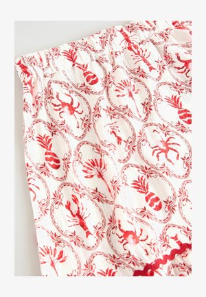 White fabric featuring a red lobster and pineapple print within oval frames, finished with a textured red trim at the waistband.