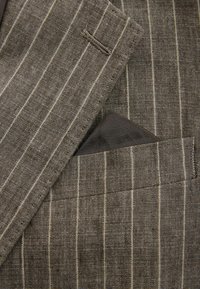 Gray striped blazer featuring a textured fabric with narrow white stripes and a small pocket square in the chest pocket.