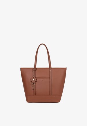 Brązowa skórzana torba typu tote z podwójnymi uchwytami, przednią kieszenią i brelokiem w kształcie kwiatu, pokazana na białym tle.