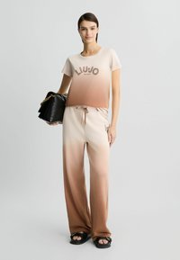 Liu Jo gradient t-shirt in beige to brown, featuring a logo print. Paired with matching wide-leg pants and black sandals.