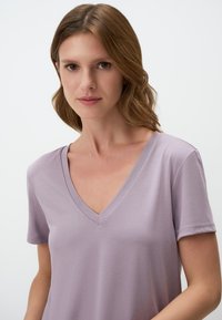T-shirt a maniche corte, con scollatura a V in un delicato color lavanda, realizzata in tessuto morbido con una superficie liscia e cuciture minime, caratterizzata da una vestibilità rilassata.