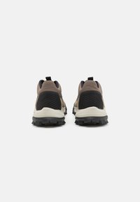 Chaussures de trail avec une tige en textile brun et noir, semelle extérieure en caoutchouc, talon renforcé et tirette pour un enfilage facile. Conçues pour une utilisation en extérieur.