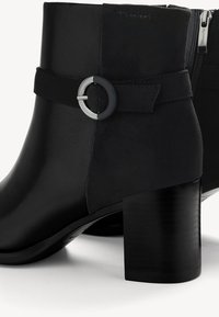 Mustad mustad nahast ja sametist ankle saapad, millel on ümmargune pandla aktsent, tekstuuritud viimistlus ja paks konts. Küljel on lukk.