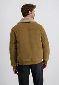Bruine corduroy jas met een tan faux schapenvacht kraag, ribbelstructuur en elastische manchetten. Heeft een rechte snit en een detail bij de rugnaad.