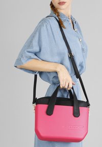 Borsa a tracolla rosa e nera con un design strutturato, dotata di due manici e di una tracolla removibile. Finitura testurizzata, logo impresso.