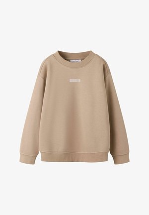 Beige crewneck-tröja med ribbade muddar och fåll, med liten vit text centrerad på bröstet.