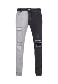 Jeans skinny bicolor con una pierna izquierda de gris claro y una pierna derecha de gris oscuro, desgastados con desgarros y un acento de logo en la parte inferior de la pierna.