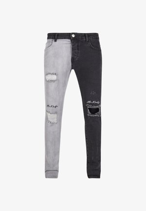 Tweekleurige skinny jeans met een lichtgrijze linkerpijp en een donkergrijze rechterpijp, beschadigd met scheuren, en een logo-accent op de onderkant van de pijp.