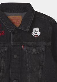 Czarna dżinsowa kurtka Levi's z czerwonymi napisami i wszywką mrugającego Myszki Mickey na górnej części przedniej kieszeni.