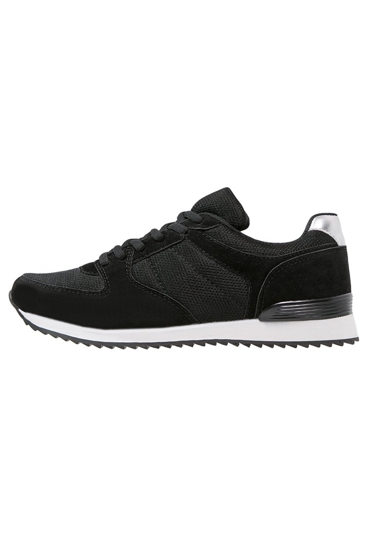 Chaussure de sport noire avec tige en mesh et en daim, bout rond, design à lacets, accents argentés sur le talon et semelle extérieure blanche avec un motif de traction.