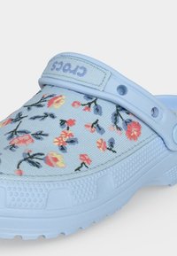 Φωτεινά γαλάζια Crocs clog με υφασμάτινο πάνω μέρος με floral σχέδιο και ρυθμιζόμενο λουράκι στη φτέρνα με το λογότυπο "Crocs".