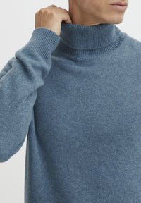 Pull à col roulé bleu clair en matériau tricoté doux. Doté d'un col et de poignets côtelés, avec une coupe décontractée et une texture minimaliste.