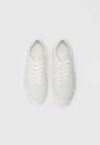 Pair of white perforated leather sneakers with laces, viewed from above on a plain white background.