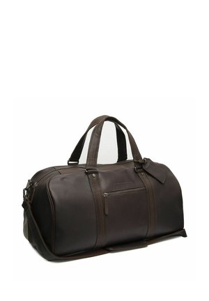 Bolsa de viaje de cuero marrón oscuro con doble asa, bolsillo exterior con cremallera y correa de hombro desmontable sobre un fondo blanco.