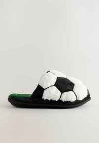 Sort og hvid blød hjemmesko designet til at ligne en fodbold, med en tekstureret overflade og grøn indersål. Sålen er sort.