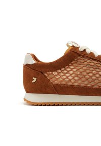 Zapatillas de ante marrón con detalles de malla, acentos blancos y suela de goma beige. Presenta cordones redondos y un logo en el lateral.