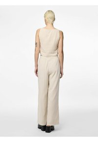 Beige tvådelad outfit som består av en ärmlös topp och vida byxor, tillverkad av textil som har en strukturerad yta, med elastisk midja och avspänd passform.