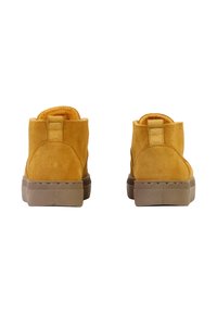Bottes de cheville en daim jaune avec une surface texturée, dotées d'une languette à l'arrière et d'une semelle en caoutchouc beige. Forme arrondie avec des détails de couture.