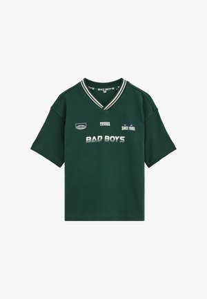 Dunkelgrünes Kurzarm-V-Ausschnitt-Shirt mit weiß gestreiftem Kragen und aufgedrucktem Text "BAD BOYS", "SOCCER LEAGUE" und "SINCE 1988" auf der Vorderseite.