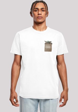 White cotton t-shirt featuring a pocket design with a graphic of a small creature and the words “PRECIOUS CARGO” on a tan background.