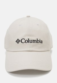 En lys beige baseball cap laget av bomull med buet skygge. Har det svarte "Columbia"-logoen brodert på framsiden.
