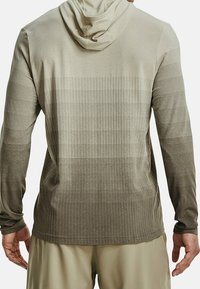 Maglia a maniche lunghe con cappuccio di colore beige, caratterizzata da un tessuto testurizzato con strisce orizzontali e un effetto sfumato. Include un cappuccio aderente e polsini.