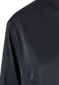 Donkerblauwe satijnen blouse met een soepele textuur, hoge kraag en subtiele glans. Heeft schone stiksels langs de schoudernaad.