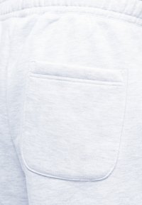 Τσέπη σε ανοιχτό γκρι φόρμα με ορατή ραφή και λεπτομέρεια ελαστικής μέσης, που δείχνει απαλή και άνετη υφή υφάσματος.