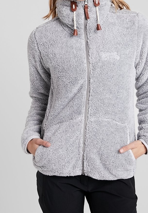 Veste polaire gris clair, douce et zippée, avec col montant, capuche à cordon, poches latérales, portée par une personne les mains dans les poches.