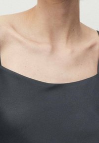 Top noir sans manches avec un décolleté carré, fabriqué en tissu lisse, mettant en valeur un design minimaliste et une texture douce.