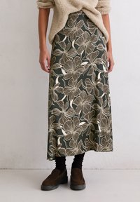 Jupe maxi en vert foncé avec un motif floral beige. Le tissu est doux et fluide, présentant une texture lisse et une coupe décontractée.