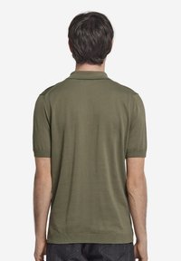 Olivgrön polo t-shirt, korta ärmar, ribbat krage och ärmslut, slät textur, utan synliga mönster eller detaljer i hårdvara.