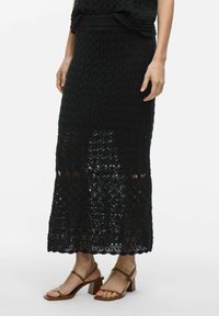 Jupe maxi noire en tricot avec un motif texturé et ajouré. Elle présente une taille côtelée et des détails en dentelle élaborés à l'ourlet.
