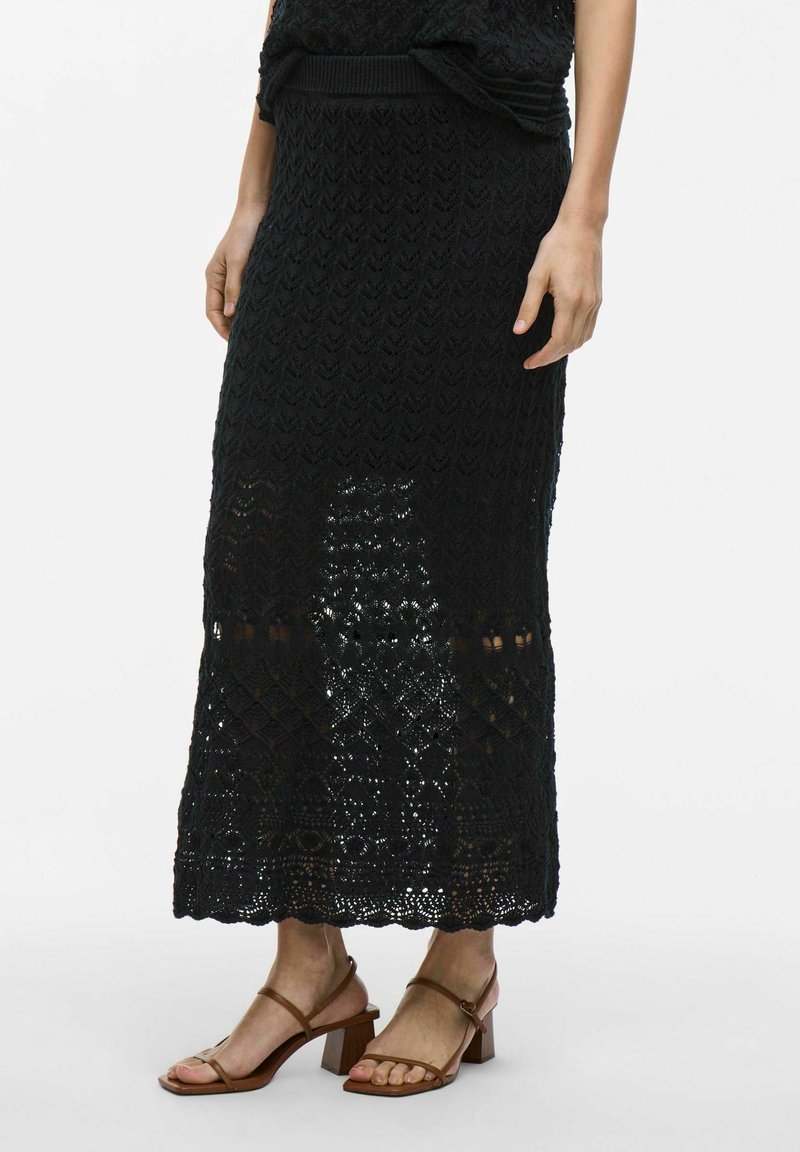 Jupe maxi noire en tricot avec un motif texturé et ajouré. Elle présente une taille côtelée et des détails en dentelle élaborés à l'ourlet.
