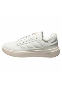 Sneaker atletico bianco con una superficie liscia, design con lacci e una suola leggermente rialzata. Presenta tre strisce diagonali su un lato.